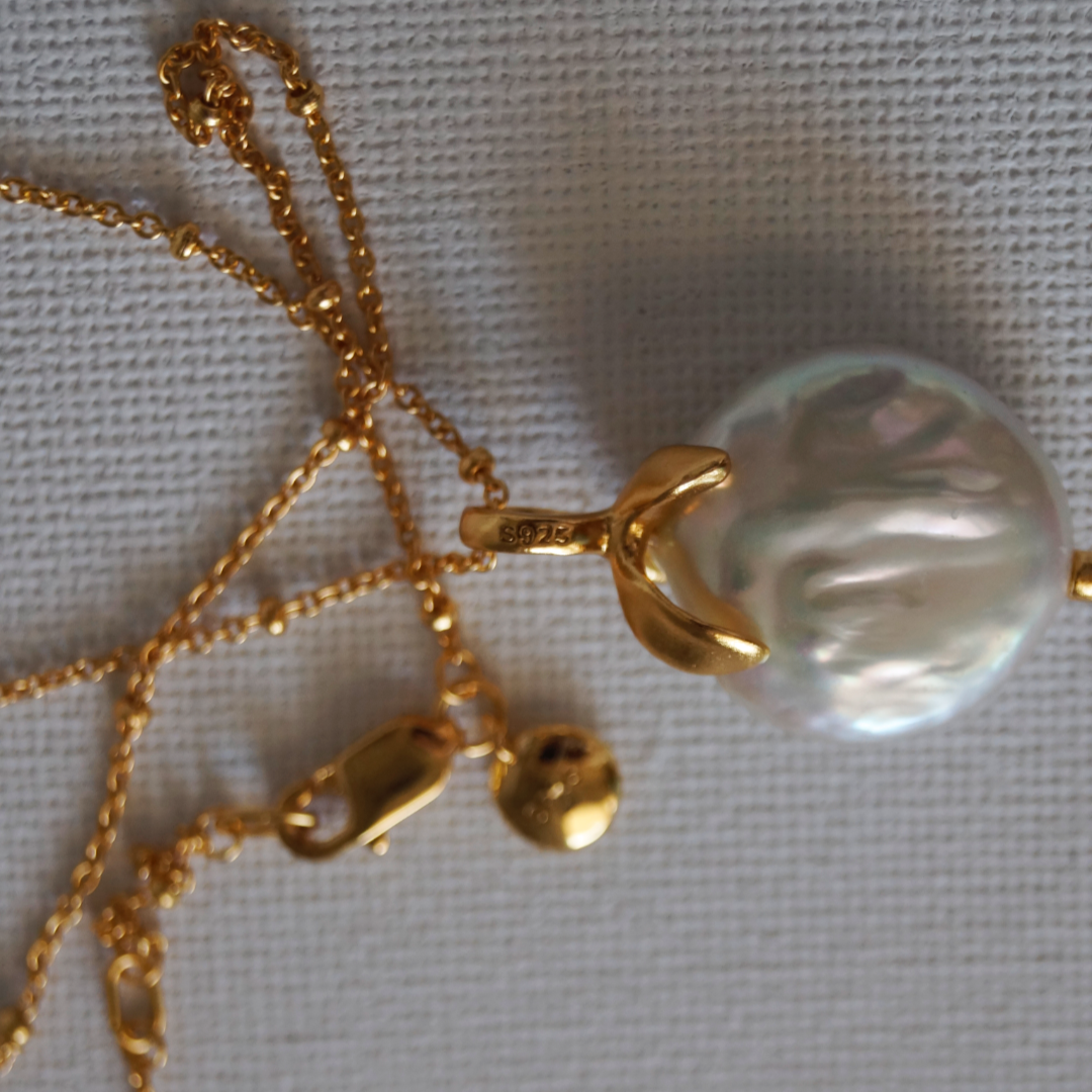 Zlatna ogrlica od srebra 925 s 18K pozlatom, ukrašena prirodnim biserom, fotografirana na neutralnoj pozadini.